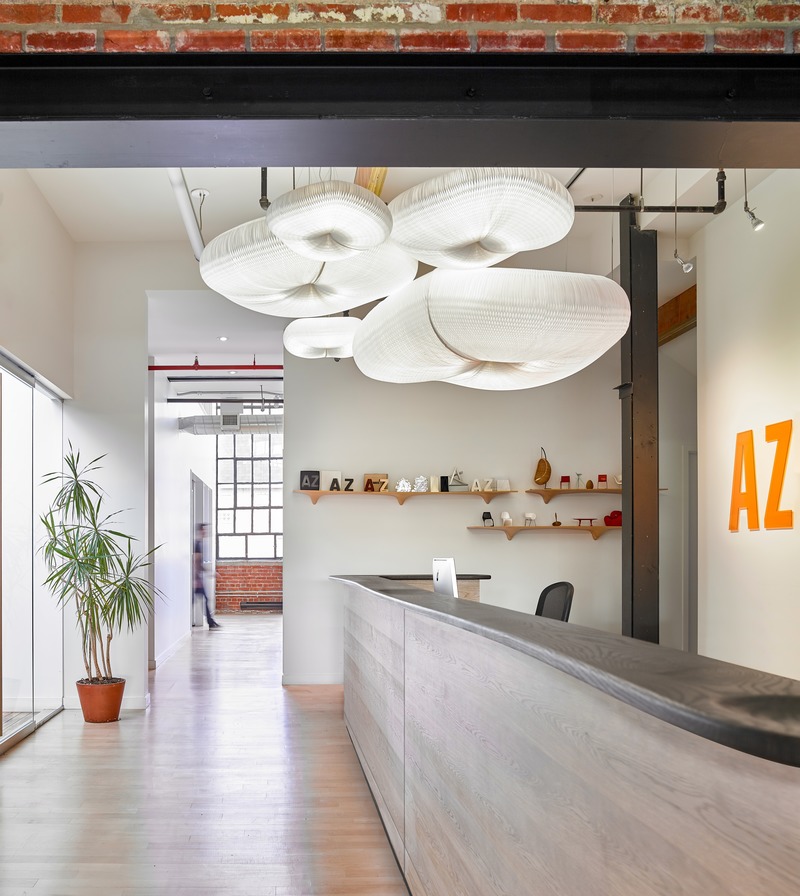 Press kit | 1513-05 - Press release | Azure Publishing Office - Dubbeldam Architecture + Design - Commercial Interior Design - An assemblage of five pendants are clustered like cumulus clouds and float above the reception desk whose sinuously organic wood top is crafted by the Brothers Dressler. - Photo credit: Scott Norsworthy