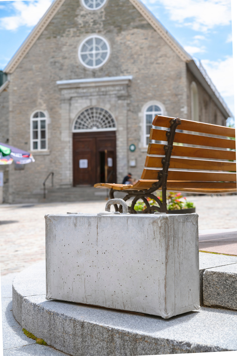 Dossier de presse | 2402-04 - Communiqué de presse | PASSAGES INSOLITES 8e édition : l'art prend ville! - EXMURO arts publics - Évènement + Exposition -   <p class="">Giorgia Volpe (Québec, Québec), "Les valises", 2021 </p><p class=""><br></p><p class="">Laissées à l’abandon dans la ville, les valises de Giorgia Volpe semblent avoir été déposées au passage puis oubliées, égarées ou volontairement cédées par leur porteur. Les bagages suspects ne renferment pourtant pas de biens personnels à saisir ou de trésors à découvrir : ils sont intégralement composés de béton massif qui en écarte tout usage. Figées ainsi dans la matière lourde et inerte, les valises obsolètes renvoient à la stagnation récente du nomadisme et des migrations humaines. </p>   - Crédit photo : Stéphane Bourgeois_EXMURO