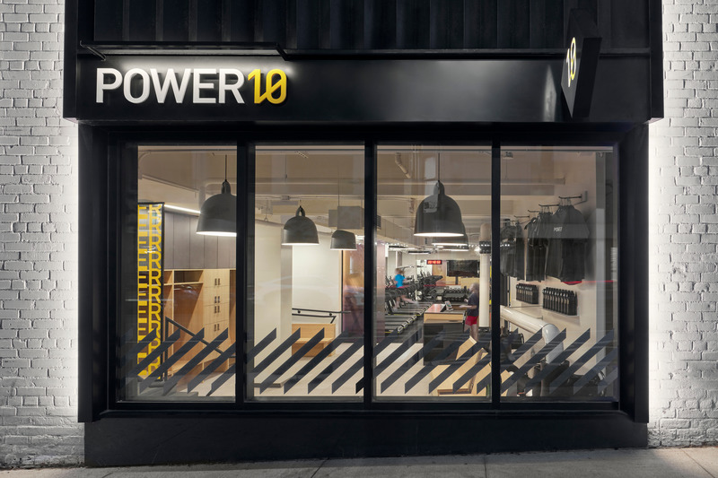 Dossier de presse | 1513-04 - Communiqué de presse | Power10 Fitness - Dubbeldam Architecture + Design - Design d’intérieur commercial -  The storefront window reveals a sophisticated interior, defined by bold graphics and top-of-the line fitness equipment, showcasing a unique and elevated fitness club experience.<br>  - Crédit photo : Riley Snelling