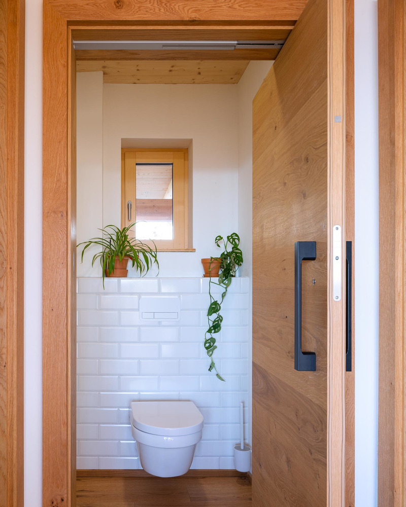 Press kit | 2506-09 - Press release | Place to be: Ecological Building with Design - Agrob Buchtal - Residential Architecture - In the WC, the clear line with regard to design and materials was maintained: plenty of wood, a little greenery, constructive refinements such as the space-saving door and ceramic tiles from the District series with Hytect coating, whose special advantages also and especially come in useful in the quiet little room.<br style=""> - Photo credit: ourplacetobe