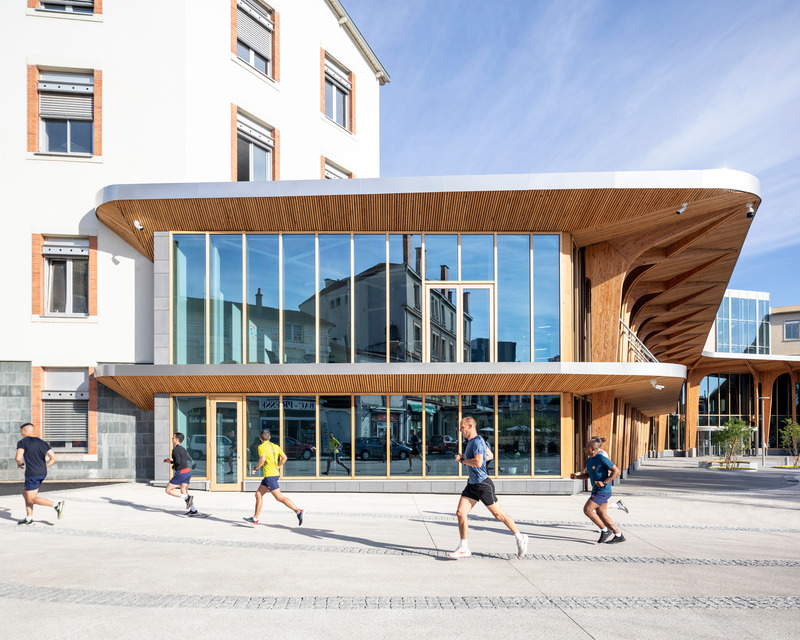 Dossier de presse | 899-02 - Communiqué de presse | La Canopée : Nouvel accueil du siège social Michelin - Encore Heureux Architectes,  Construire et Base - Architecture commerciale - Coureurs sur la place des Carmes et façade du bâtiment d'accueil - Crédit photo : Cyrus Cornut