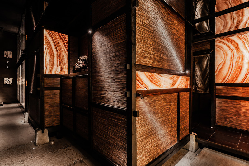 Press kit | 5577-02 - Press release | T0 Sumibi Yakiniku | Shibuyanaka Sushi - Nong Studio - Commercial Interior Design - <p>To make wood partitions structure, old timber of Douglas fir discarded in Shanghai old buildings is recycled use and burnt through deep charcoal burning to create unique scale patterns. Upon structure that inlaid with luminous red-yellowish onyx with a special pattern like multiple layers of flames, several materials and LED light sheets is combined to realize double-sided translucent effect.</p> - Photo credit: Hei Nong
