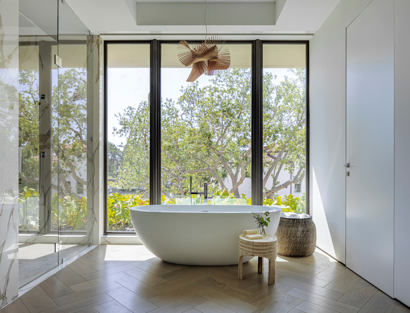 Dossier de presse | 2757-30 - Communiqué de presse | Strang Design Realizes Sustainable Waterfront Residence - Strang Design - Architecture résidentielle -  The primary bathroom highlights the freestanding statement tub and sculptural pendant, allowing the focal point of the background to be the surrounding landscape.   - Crédit photo : Kris Tamburello Photography