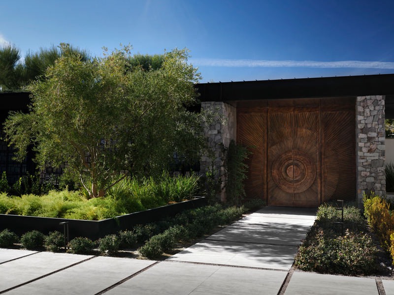 Press kit | 6087-03 - Press release | Family Connections: a Five-Star Retreat in the Desert Southwest - Daniel Joseph Chenin, Ltd. - Residential Interior Design - A landscaped path leads to a set of massive ornamental bronze doors, emblazoned with a pattern of rings radiating outward, symbolizing the house as a central point from which activity radiates in all directions. - Photo credit: Douglas Friedman