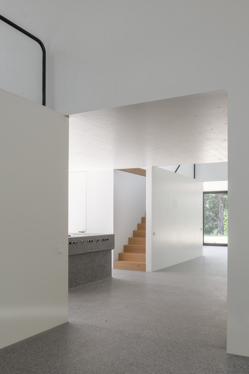 Dossier de presse | 6863-01 - Communiqué de presse | Wooden House by the Lake - Appels Architekten - Architecture résidentielle - <p>View through the open living area showing the central kitchen.</p> - Crédit photo : © Florian Holzherr