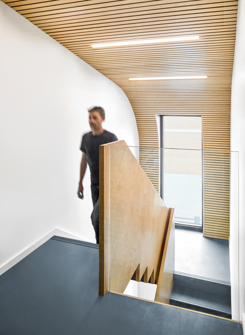 Dossier de presse | 1513-19 - Communiqué de presse | Dubbeldam Office - Dubbeldam Architecture + Design - Architecture commerciale -  The carefully crafted stair railing accentuates the dramatic shape of the steps, while the curved ceiling with Baltic birch slats and integrated lighting creates a spatial flow to the third floor.<br>  - Crédit photo : Scott Norsworthy