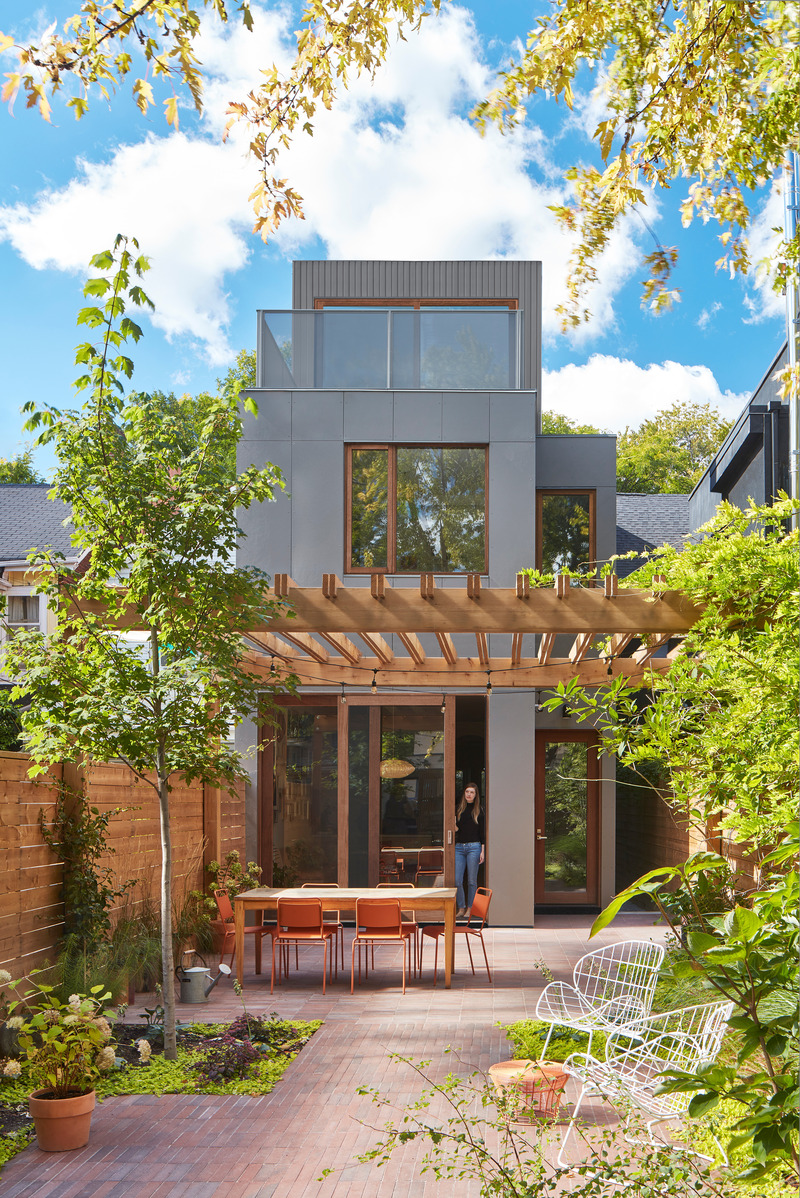 Dossier de presse | 1513-18 - Communiqué de presse | Flow House - Dubbeldam Architecture + Design - Architecture résidentielle - The design of the rear garden continues the strategy of of compression and expansion, achieved through planting beds and defined areas for dining, lounging and play. The exterior wall cladding, comprised of grey-toned cement board panels, is a subtle backdrop to the warm brick pavers and lush planting. - Crédit photo : Riley Snelling