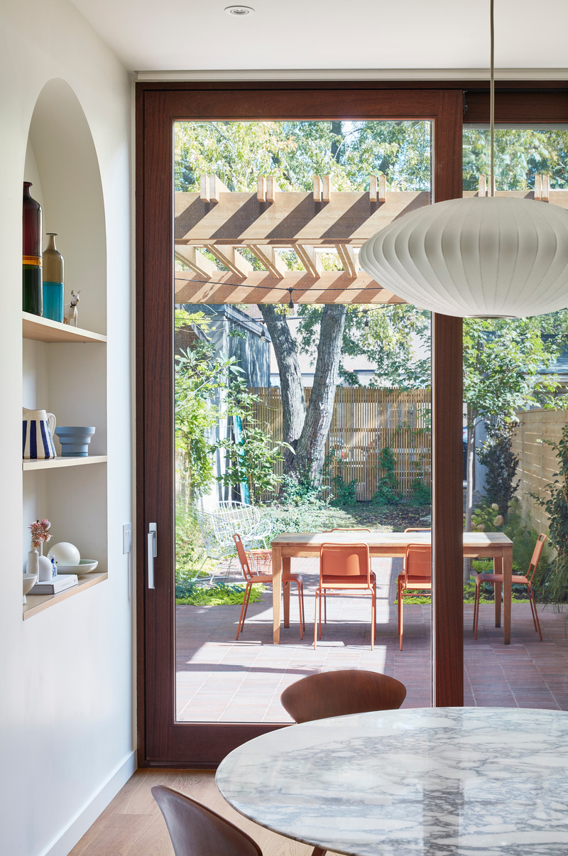 Dossier de presse | 1513-18 - Communiqué de presse | Flow House - Dubbeldam Architecture + Design - Architecture résidentielle - Floor to ceiling mahogany doors bring the outdoors in. An overhead trellis shelters the outdoor dining room set on a brick terrace. An arched alcove displays the owners’ collection of personal objects collected from their travels. - Crédit photo : Riley Snelling