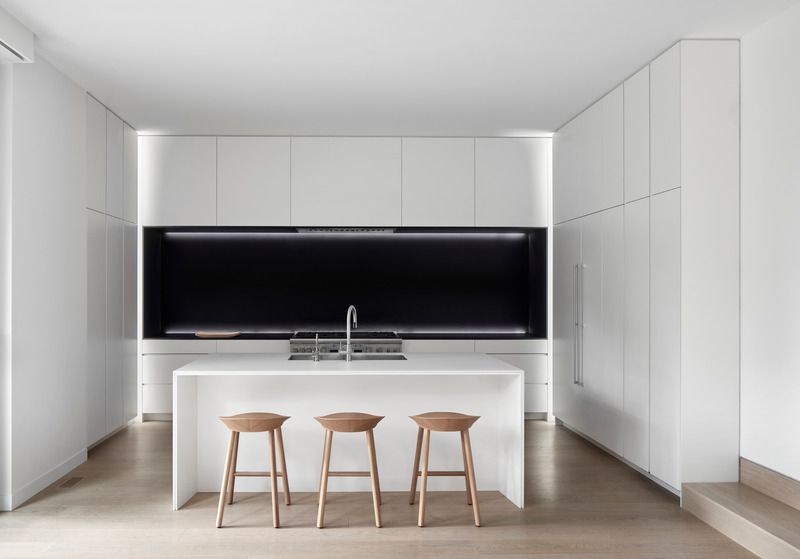 Dossier de presse | 1728-03 - Communiqué de presse | West End Renovation - Akb Architects - Architecture résidentielle - Matte black finishes surrounding the cooking range express a singular recessed volume in an otherwise all-white kitchen. Counter stools by e15. - Crédit photo : Shai Gil