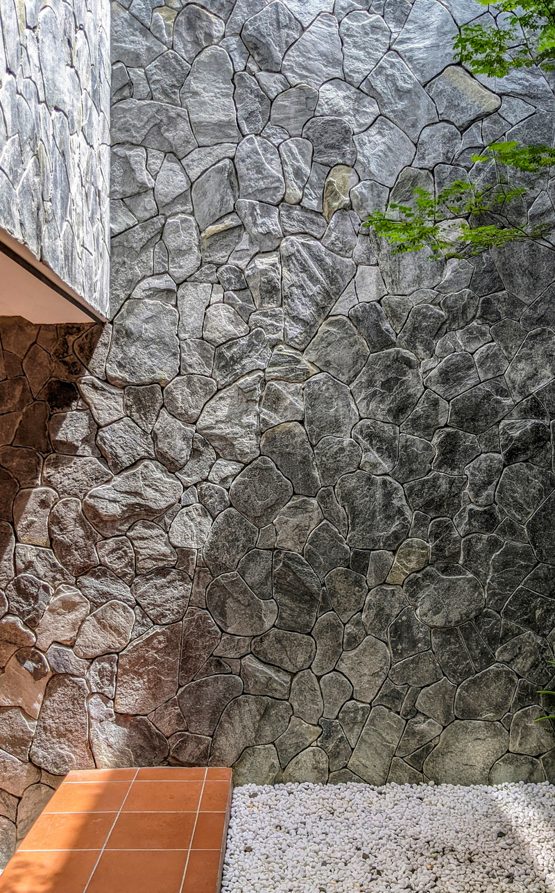 Dossier de presse | 7017-02 - Communiqué de presse | Red House - SAVA - Architecture résidentielle - Courtyard - centered around tree, pebbles, stone, and terracotta. - Crédit photo : Aron Beh