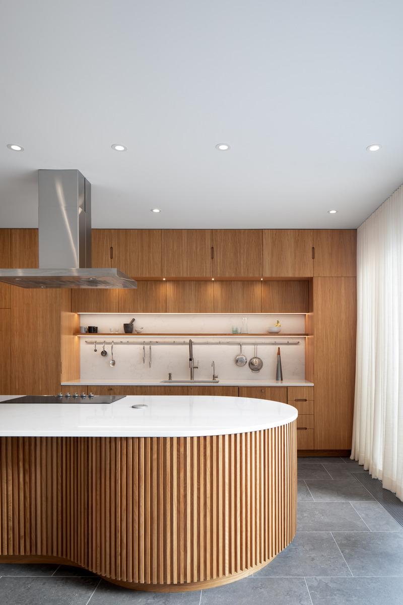 Dossier de presse | 2054-03 - Communiqué de presse | Résidence Grey - RobitailleCurtis - Architecture résidentielle -  Ilot courbé en lattes de chêne blanc avec cuisine en chêne blanc en arrière-plan  - Crédit photo : Adrien Williams