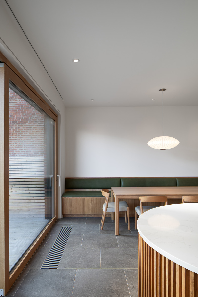 Dossier de presse | 2054-03 - Communiqué de presse | Résidence Grey - RobitailleCurtis - Architecture résidentielle -  Vue de l'îlot courbé avec banquette en chêne blanc dans la salle à manger en arrière-plan - Crédit photo : Adrien Williams