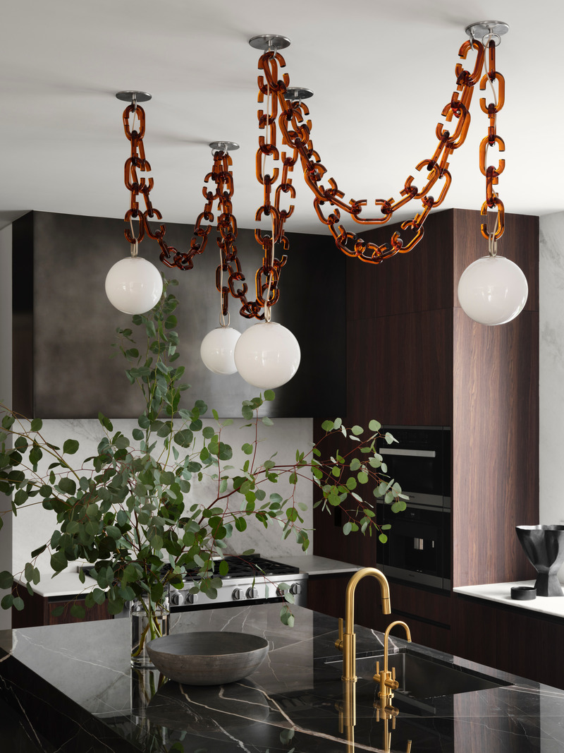 Press kit | 6087-05 - Press release | Palm Residence: A Harmonious Fusion of Hospitality and Home - Daniel Joseph Chenin - Residential Interior Design - Custom Cerine swagged chandelier by Trueing above the stone wrapped main island serves as the focal point within the kitchen. - Photo credit: Douglas Friedman