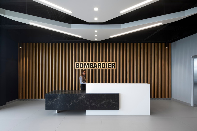 Dossier de presse | 1387-11 - Communiqué de presse | NEUF architect(e)s réalise un nouveau campus aéronautique de hautes technologies sur l’aéroport international Pearson, Toronto - NEUF architect(e)s - Architecture industrielle -  <p class="">L'espace d'accueil des bureaux de Bombardier intègre des déflecteurs en forme d'ailes au niveau du plafond et un bureau « flottant » inspirés de l’univers de l’aéronautique.</p>  - Crédit photo : Adrien Williams