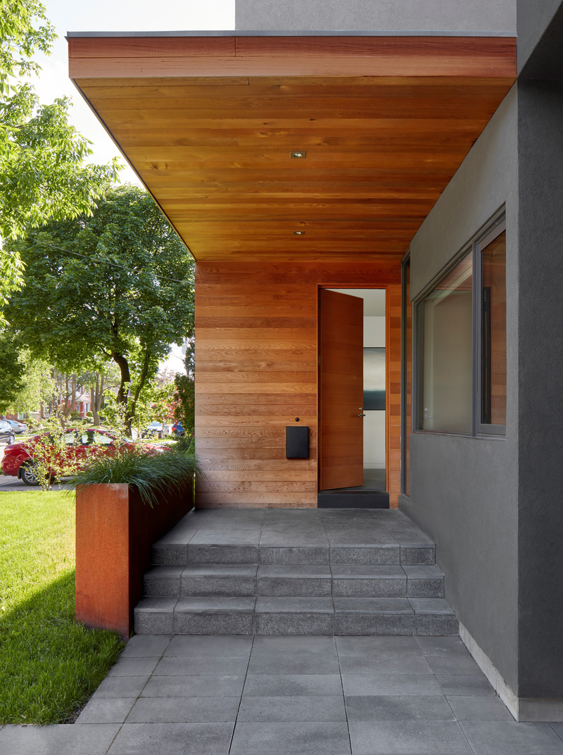 Dossier de presse | 1513-13 - Communiqué de presse | Shift House - Dubbeldam Architecture + Design - Architecture résidentielle - A cantilevered porch overhang, clad in warm cedar that wraps down the elevation and covers the front door, creates a bold and inviting entrance. The driveway’s granite pavers seamlessly transition onto the entrance porch, adding to the cohesive design. - Crédit photo : Shai Gil
