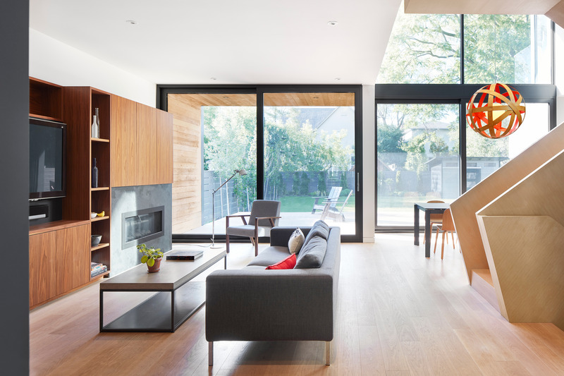 Dossier de presse | 1513-13 - Communiqué de presse | Shift House - Dubbeldam Architecture + Design - Architecture résidentielle - Large windows connecting the interior spaces to the outdoors blur the boundaries between inside and outside. Within the living room, the use of walnut millwork and a slate fireplace surround offers a striking contrast to the light-colored white oak flooring and stair. - Crédit photo : Riley Snelling