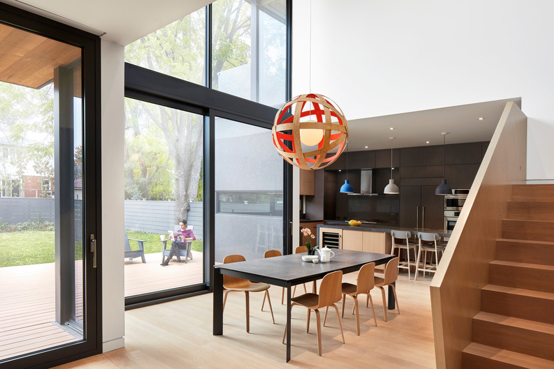 Dossier de presse | 1513-13 - Communiqué de presse | Shift House - Dubbeldam Architecture + Design - Architecture résidentielle - The dining room sits within a double-height atrium with a fully-glazed rear facade that provides an expansive view of the neighbourhood’s mature trees, inviting natural light deep into the interior and magnifying the grandeur of this modest space. - Crédit photo : Shai Gil