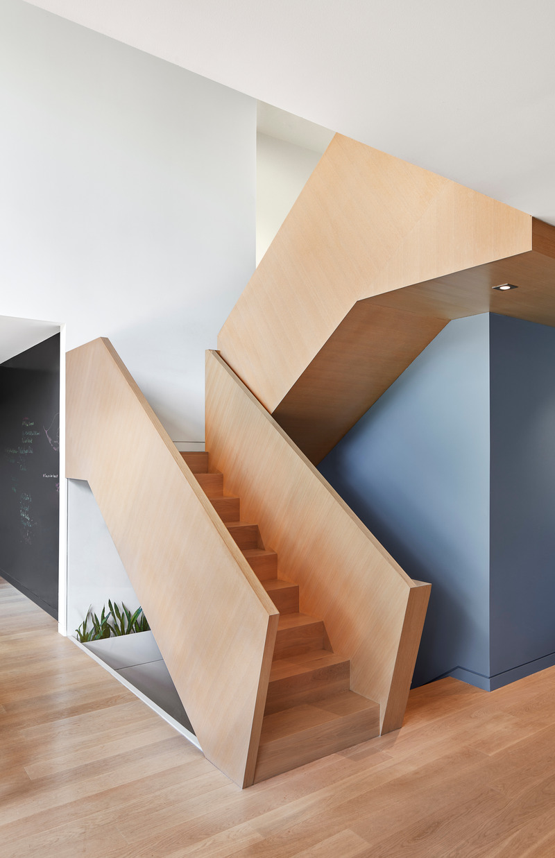 Dossier de presse | 1513-13 - Communiqué de presse | Shift House - Dubbeldam Architecture + Design - Architecture résidentielle - The monolithic stair guard's diagonal wood grain imparts a sense of craftsmanship while also evoking a feeling of movement and energy. Walls painted in shades of grey-blue serve as further defining elements against the white walls and oak flooring. - Crédit photo : Riley Snelling