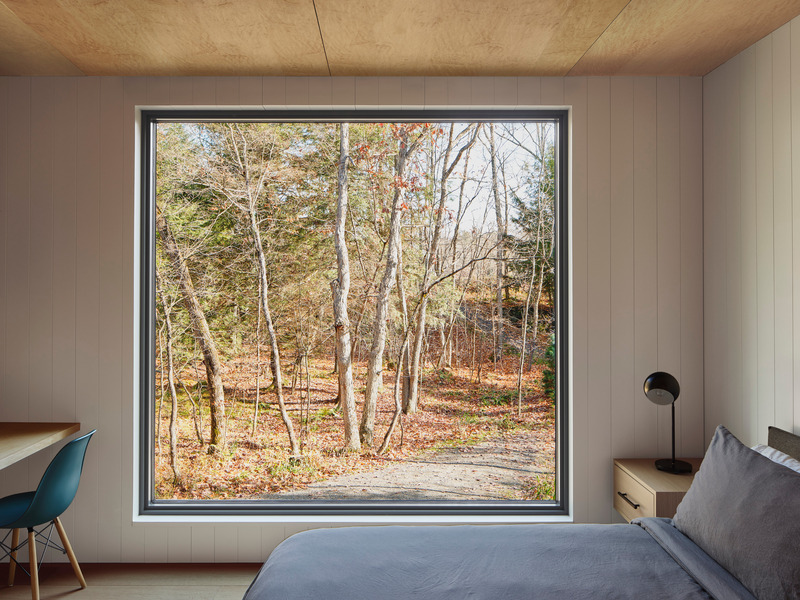 Dossier de presse | 1513-20 - Communiqué de presse | Bunkie on the Hill - Dubbeldam Architecture + Design - Architecture résidentielle - Located at the rear for a more peaceful environment, the bedroom offers immersive views of the forest through a large picture window. - Crédit photo : Riley Snelling