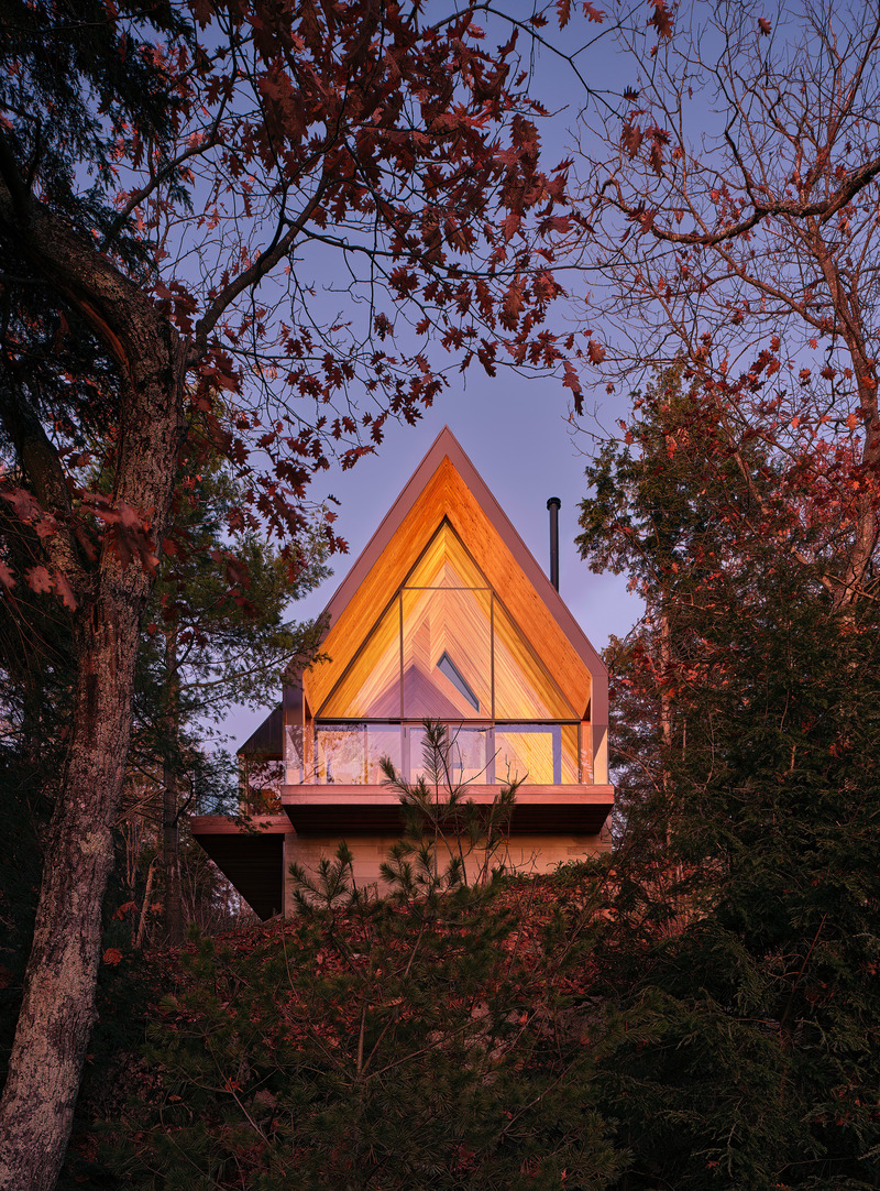 Dossier de presse | 1513-20 - Communiqué de presse | Bunkie on the Hill - Dubbeldam Architecture + Design - Architecture résidentielle - Tucked into the trees at the top of a steep slope, the Bunkie’s warm cedar interior lights up like a lantern in the evening. - Crédit photo :  Riley Snelling 