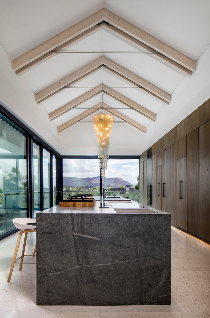 Dossier de presse | 5741-01 - Communiqué de presse | Winelands Villa: Contemporary Blend of Farmhouse & Modern Design - ARRCC - Design d’intérieur résidentiel - The main kitchen dually flows into the living room area and outdoor section, with 360 views of the surrounding mountains.<br> - Crédit photo : Adam Letch