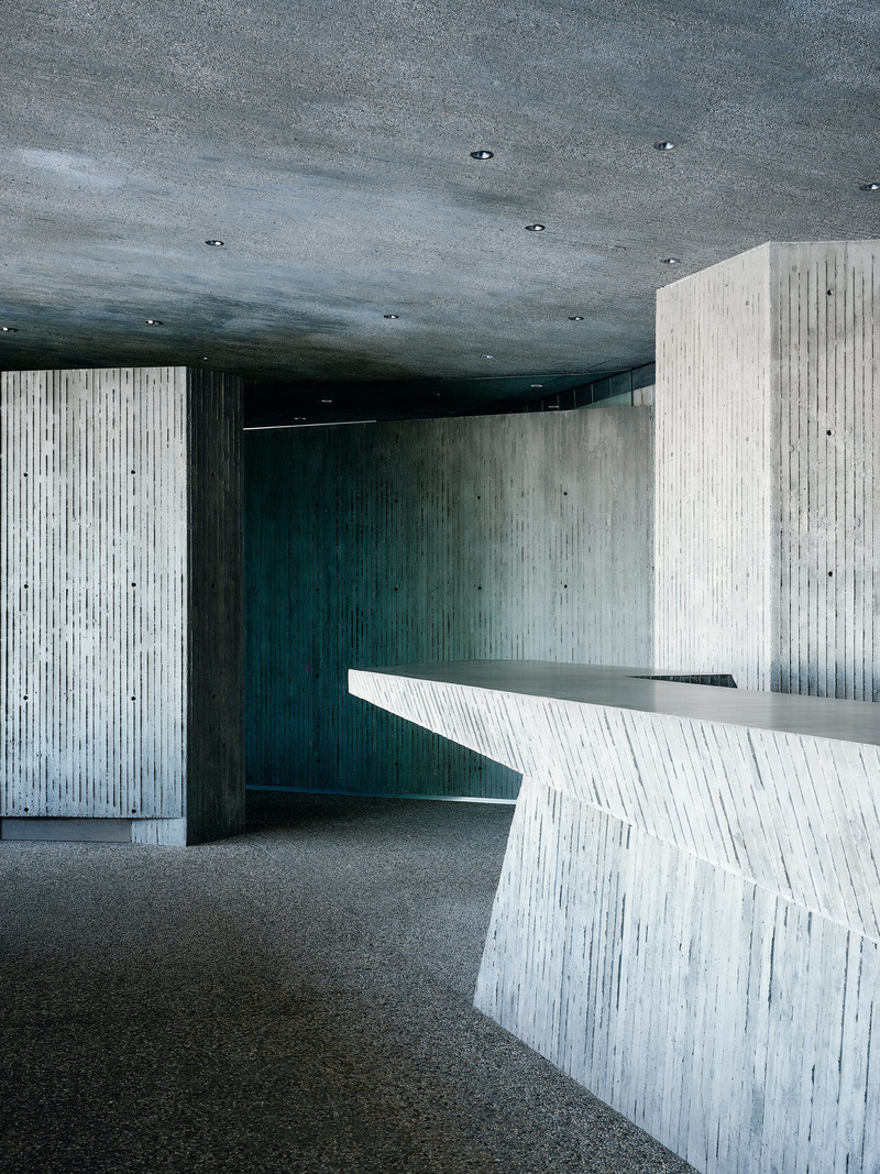 Dossier de presse | 2757-45 - Communiqué de presse | Honoring Architectural Lineage: Conner + Perry Architects Usher in a New Phase for an LA Landmark - Conner + Perry Architects - Architecture résidentielle -  <p class=""><b>Nightclub Bar:</b> The club’s one-of-a-kind concrete bar cantilevers dramatically at one end pointing toward the hidden entry to the VIP Room/Library and Restrooms.  In this image one can see the various treatments of each concrete surface.  The floors are a pebble finish, matching the walking surfaces throughout the property both inside and out.  The walls and vertical surfaces are board-formed with a 1-1/2” wide plank, a subtle variation of the wider plank utilized more sparingly in the original residence.  The countertop is highly polished and waxed, as are all the other horizontal utility and seating surfaces.  And the ceilings are board-formed but have been sand blasted to provide a subtler texture and expose more of the aggregate.</p>  - Crédit photo : Joe Fletcher Photography