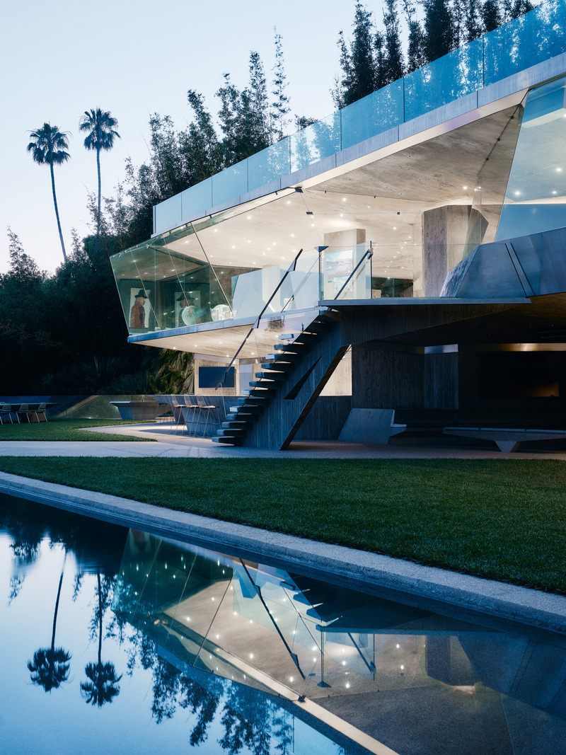 Dossier de presse | 2757-45 - Communiqué de presse | Honoring Architectural Lineage: Conner + Perry Architects Usher in a New Phase for an LA Landmark - Conner + Perry Architects - Architecture résidentielle - <p class=""><b>Lower Terrace:</b>  The newly completed lowest level of Club James. In the foreground, the new pool reflects the upper levels of the office and tennis court above in the dwindling evening sunlight.  The outdoor entertainment terrace features multiple dining areas with dramatically cantilevered concrete tables, a lounge area, full bar, and a fully functioning catering kitchen with a custom concrete and stainless-steel bar-b-que. Bordering the terrace on the south edge lies a pool with a 100-foot-long infinity edge. At the cantilevered western end of the pool is a triangular spa separated from the pool by a nearly invisible acrylic wall. Adjacent to the spa is a fire pit and cantilevered concrete bench. A restroom with outdoor glass sink and a changing room were also added.</p> - Crédit photo : Joe Fletcher Photography