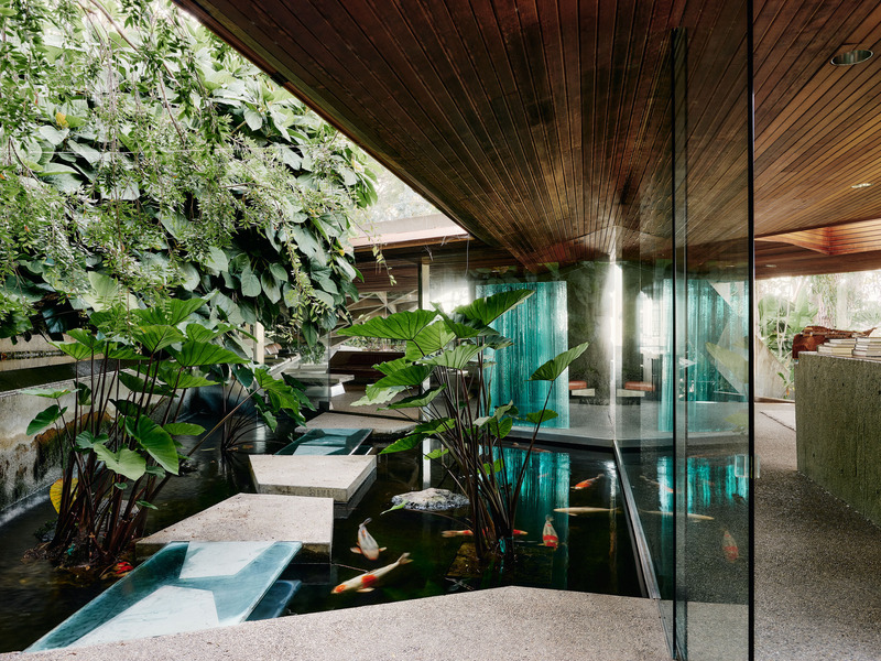 Dossier de presse | 2757-45 - Communiqué de presse | Honoring Architectural Lineage: Conner + Perry Architects Usher in a New Phase for an LA Landmark - Conner + Perry Architects - Architecture résidentielle - <p class=""><b>Sheats-Goldstein Residence:</b> View of the original Lautner-designed residence’s main entrance vestibule with a koi pond garden featuring a waterfall and glass and concrete foot bridge.  The entire entry procession and secondary spaces of the main floor are covered by a low-slung redwood ceiling that compresses the space giving it a more intimate scale and emphasizing the dramatic transition into the iconic living room space beyond.</p> - Crédit photo : Joe Fletcher Photography