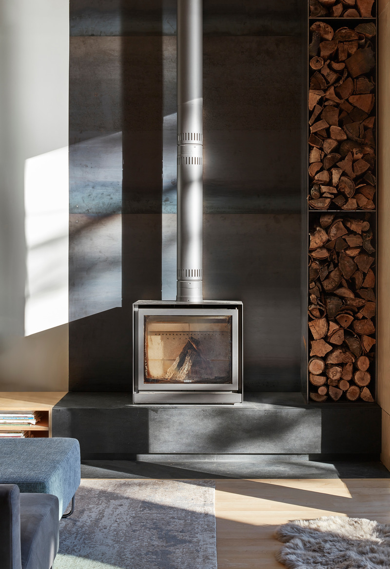 Dossier de presse | 1513-14 - Communiqué de presse | Catchacoma Cottage - Dubbeldam Architecture + Design - Architecture résidentielle -  In the living room, a freestanding wood-burning stove is set on a slate stone ledge, complemented by a custom steel firewood storage solution.  - Crédit photo : Riley Snelling